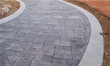 Gray paver walkway bordered by cement