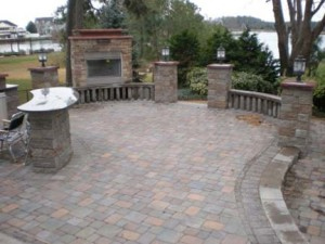 Outdoor patio with fireplace and bar using brick pavers of various colors of red